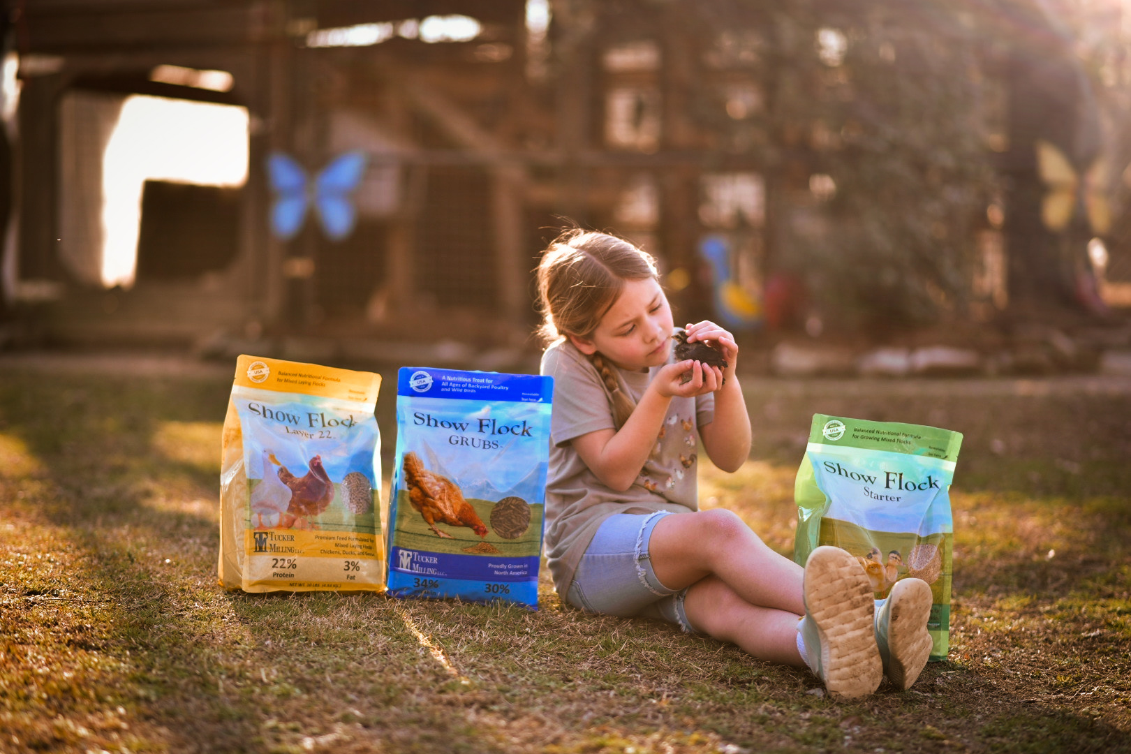 Tucker Milling Feeds bags of show flock with a little girl holding a chick